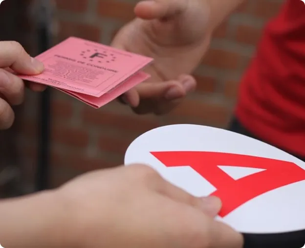 Une personne tient un permis de conduire rose, une autre une plaque A.