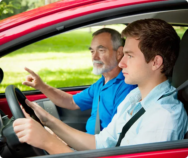 Un homme plus âgé enseigne la conduite à un jeune homme.