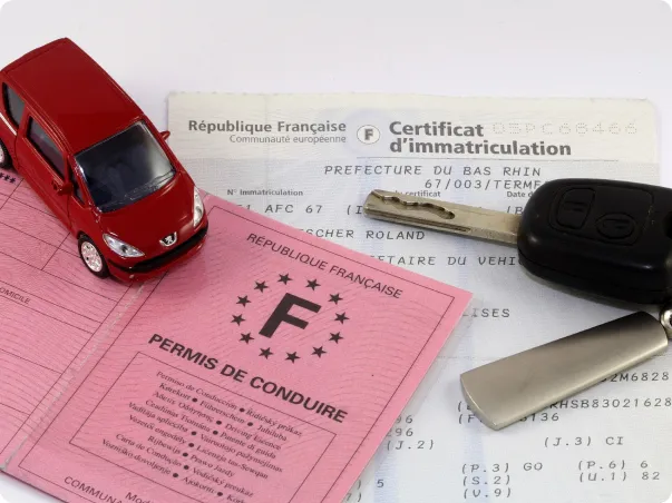 Permis de conduire français, certificat d'immatriculation, clé de voiture, et modèle réduit.