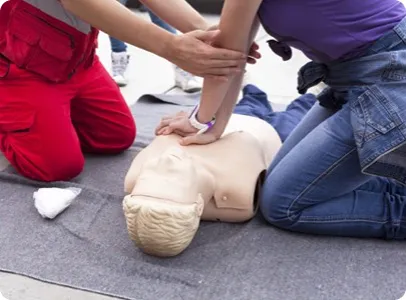 Deux personnes effectuent une réanimation cardio-pulmonaire (RCP) sur un mannequin.