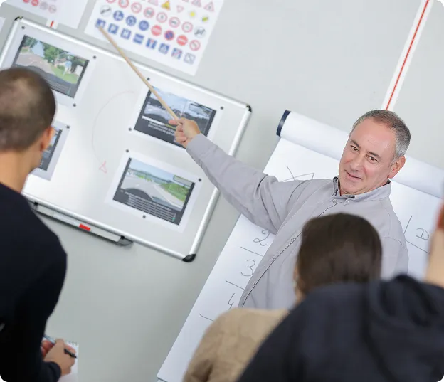 Homme enseignant des règles de conduite routière à des étudiants avec un pointeur.